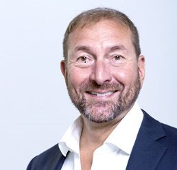 Man with light brown hair in a professional portrait wearing a white button down and blue blazer.