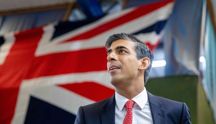 Side view of former PM Rishi Sunak standing in front of a Union Jack flag